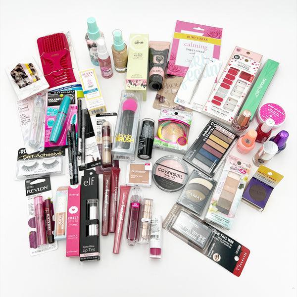 A lot of 50 Deal Society Wholesale Mixed Makeup & Beauty Tools, including lipsticks, eyeshadows, foundations, nail polishes, beauty tools, mascaras, and skincare items, displayed on a white surface.